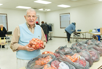 elderly man holding a bag of onions