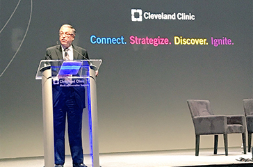 Armond Budish standing at a podium with chairs to the right