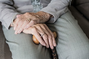Older woman has her hands folded in her lap