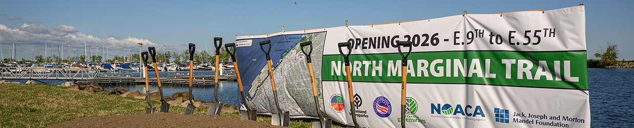 At the waterfront, a large banner promoting new construction behind shovels stuck in dirt.