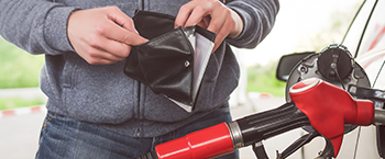 Man pumping gas with wallet open
