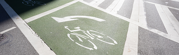 The outline of a bike and an arrow are spray painted white on the pavement of a street.