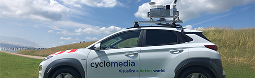 A white sedan car with Cyclomedia on the side and a camera mounted to the top.