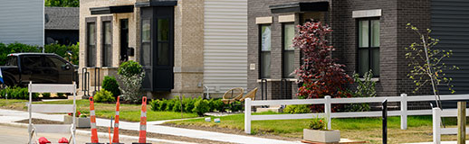 Two modern looking housing buildings with small yards on an empty street.