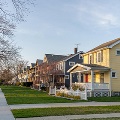 Residentialstreetlinedwithcolorfulhomesmaturetreessidewalksandneatlymaintainedlawnsinaquietsuburbanneighborhood