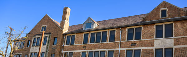 A vacant old brick building with a chain link fence around it.