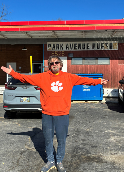 Man in a orange hoodie standing in front of his Park Avenue Muffin shop.