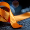 Orangeribbonlyingonatableintheshapeofanawarenessribbonloop