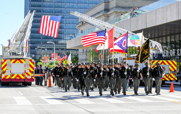 A firetruck and a group of police walking on the street holding government flags.
