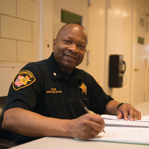 Correctional Officer in uniform sitting at desk