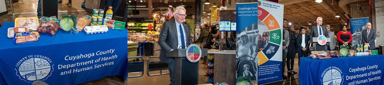 Group of people standing at a podium next to an array of food items.