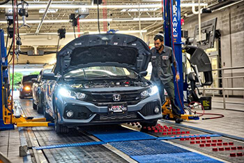 Honda with hood open in assembly line.