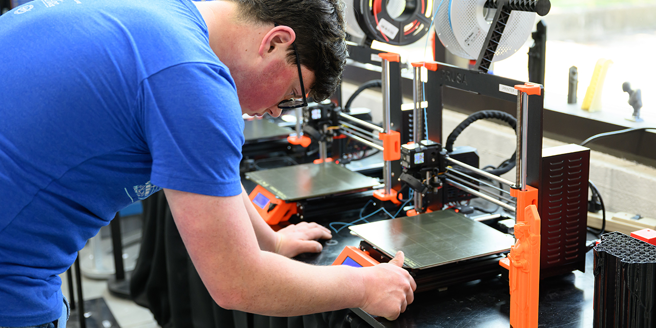 A worker calibrates a piece of machining equipment.