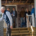 Amanisshakinghandswithapersoninfrontofahousewherepeoplearestandingonthefrontporch
