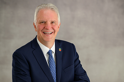 Chris Ronayne in a suit sitting and smiling