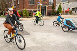 group of people bicycling near a blue bridge