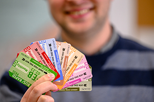 man holding colorful monthly transit passes