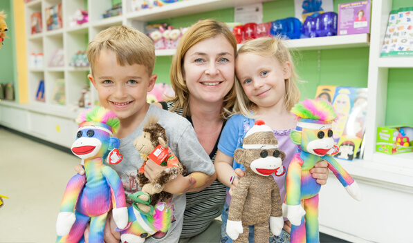 Woman smiling with 2 children holding stuffed animals