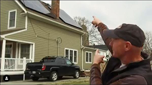 man pointing to a house that has solar panels on the roof