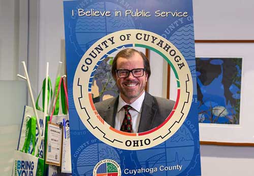 Man holding a Cuyahoga County themed sign to promote public service.