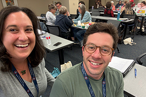 man and woman smiling in a room of tables and people