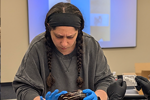 woman wearing blue gloves inspecting an object