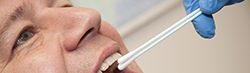 Hand in medical glove swabbing the inside of a man's cheek