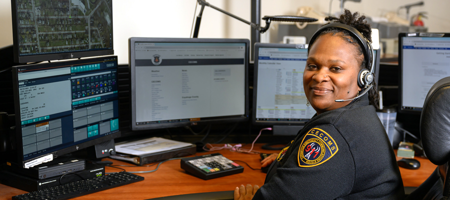A security woman sitting at a control desk wearing a headset.