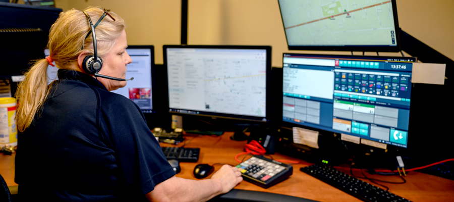 A woman working at a 9-1-1 dispatcher desk.