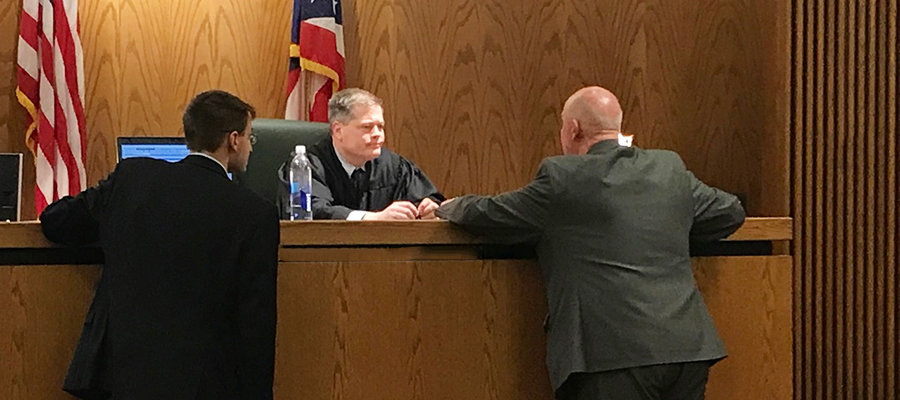 Two male lawyers standing up speaking with the judge in court.