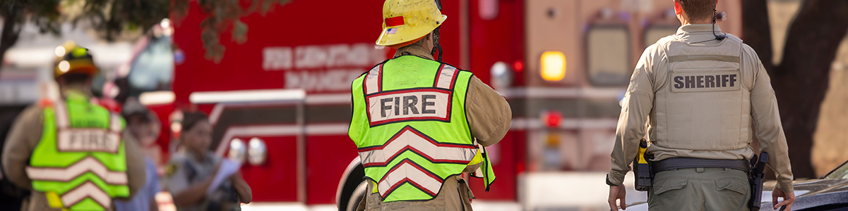 Fireman and a sheriff standing in front of an ambulance.