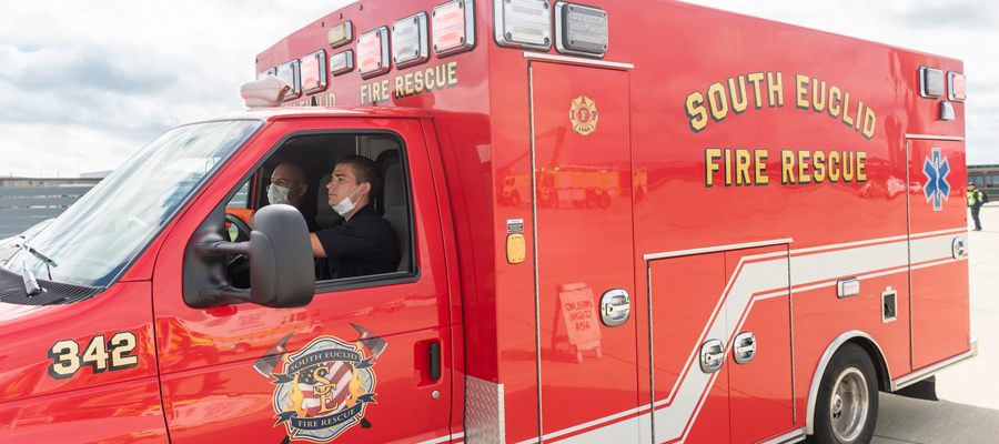 A red Cuyahoga County ambulance with a man driving.