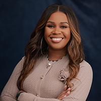 A woman is smiling and standing with her arms cross.