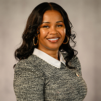 A woman is smiling and standing with her arms cross.