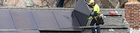 SolarCoop person installing solar panels on a roof