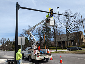construction workers putting up a sign next to a traffic light