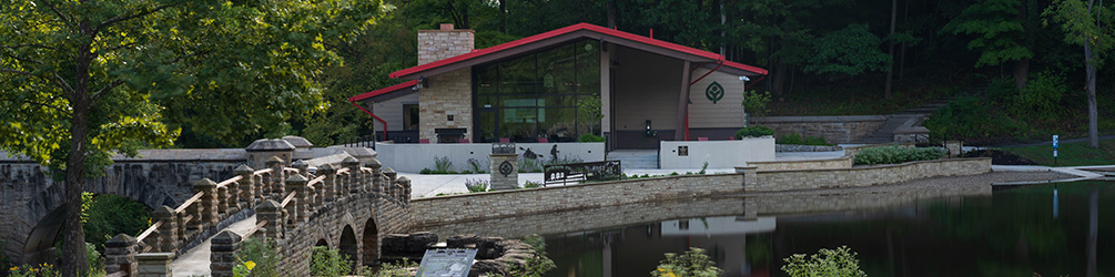 Exterior building with red room and a bridge going over water leading to it.