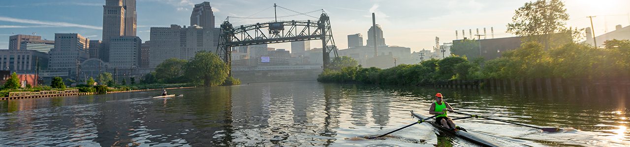 two people kayaking on the Cuyahoga River with downtown Cleveland in the background