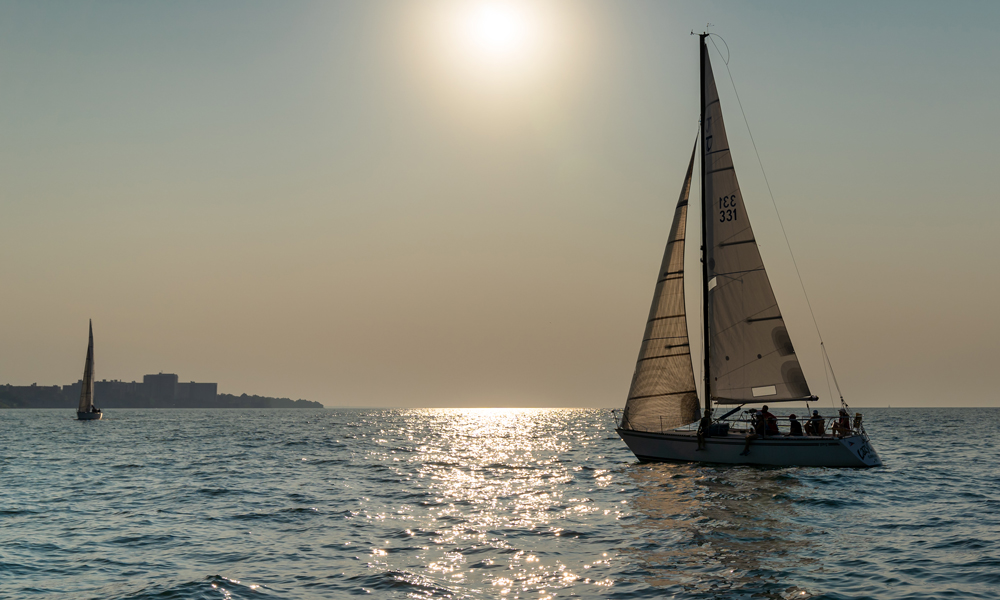 Two sailboats on Lake Erie with the sun setting in the background.