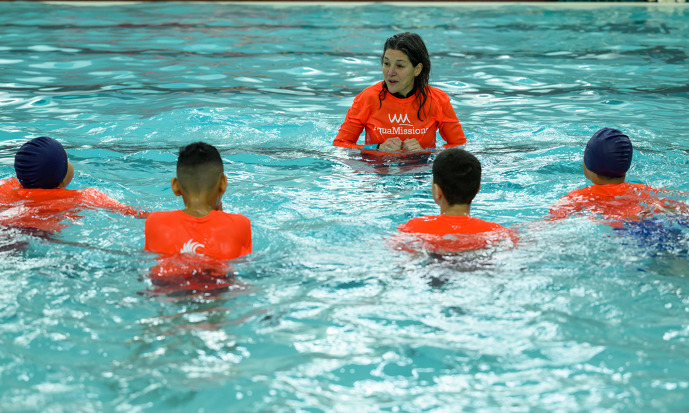 A girl instructing two kids in swim lessons in a pool.
