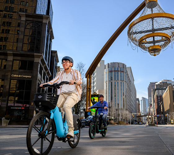 Two people riding e-bikes through downtown cleveland