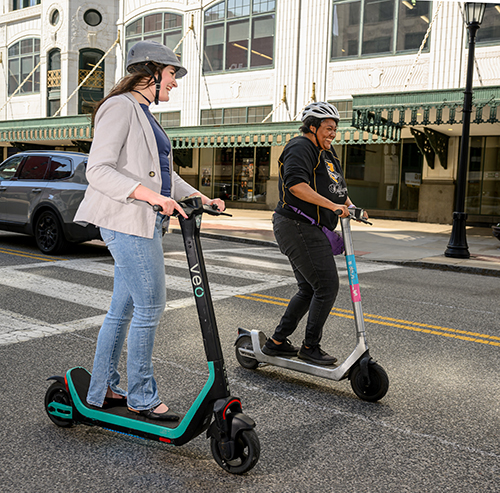 Two people riding e-scooters through downtown cleveland