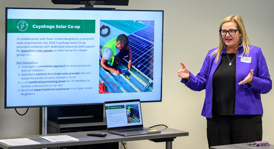 A woman standing and presenting a plan with Cuyahoga Solar Co-op on the screen.