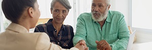 SideviewofAfrican-Americanmanshakinghandswithfinancialadviserwhilesittingbesidewife